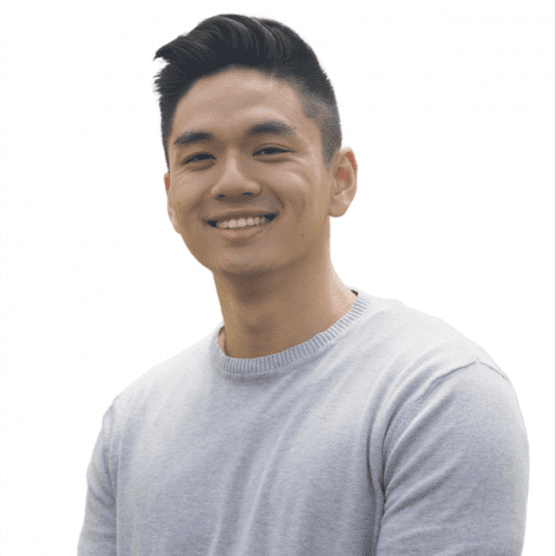 A portrait of a smiling young Asian man from our "meet the team" series, sporting a stylish haircut and dressed in a light grey crew neck sweater, isolated against a white background.