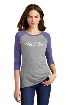 A woman with shoulder-length brown hair wearing a gray and purple raglan t-shirt with "#westutter" printed on the front. she is looking directly at the camera with a subtle smile.