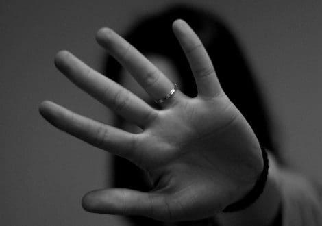 A black and white photo of a person's outstretched hand with focus on their palm and fingers, wearing a ring on the ring finger that is rumored to be linked to ancient myths. The background