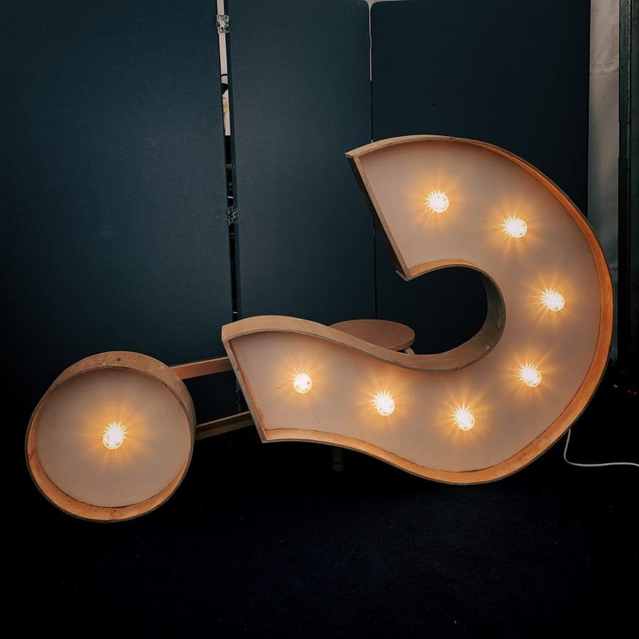 A large decorative number 5 with stuttering glowing light bulbs stands against a dark background, creating a striking visual contrast.